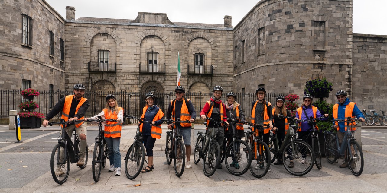 line of people on bikes in front of stone building 