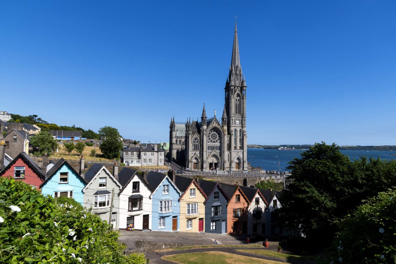 cathedral beside water behind row of colourful houses